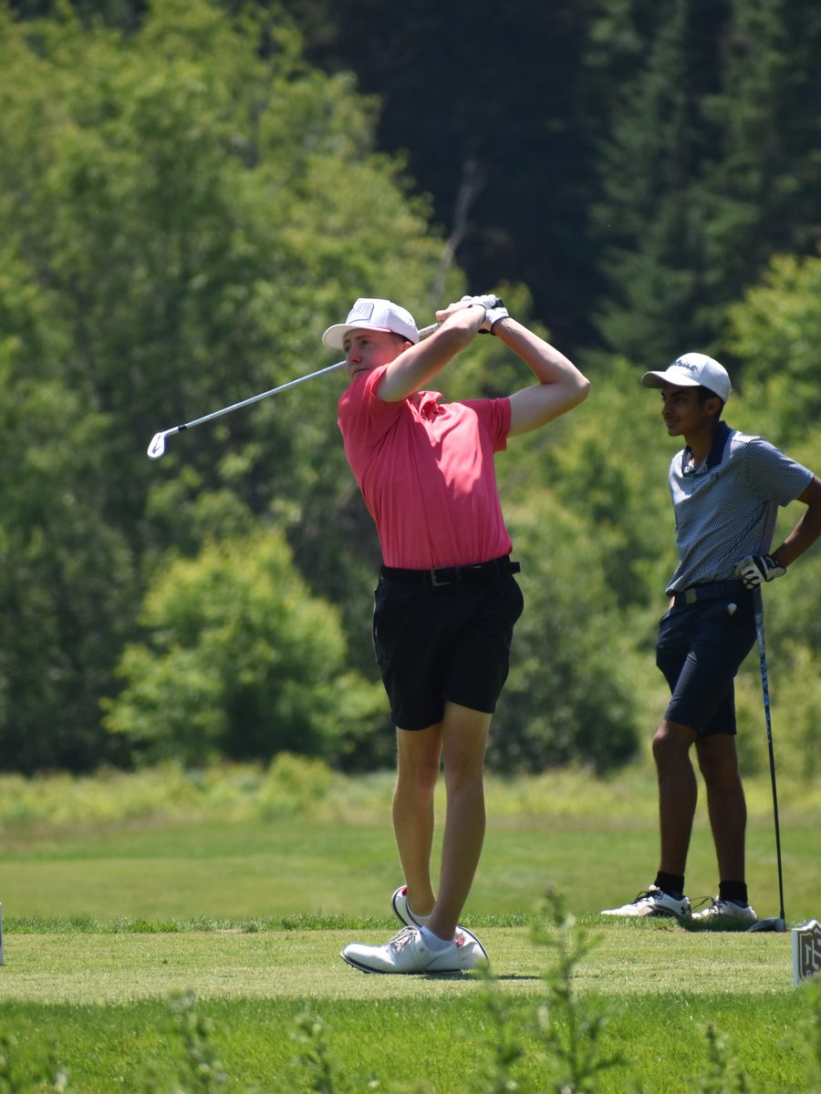 A New Hampshire high school golfer following through on a tee shot.